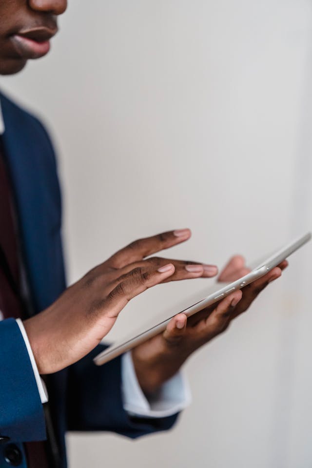 A professionally dressed man wearing a blue suit jacket examines a digital tablet, conveying themes of investment analysis, wealth management, and financial technology. This image is ideal for Grey Capital Investments, illustrating expertise, trust, and modern financial services.